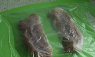 Дальше кусочки мяса накрываем пленкой и отбиваем кухонным молотком.