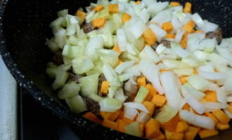 С луковицы снимите шелуху, ополосните и измельчите острым ножом. Сладкий перец нарежьте кубиком, предварительно промыв и очистив его от внутренностей. Морковь почистите овощечисткой, нарежьте кубиком. Сложите овощи к мясу и готовьте 20 минут, не забывая переворачивать.