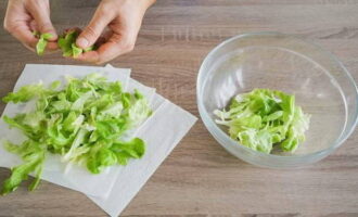 Салатные листья промойте под водой, выложите на бумажные полотенца, чтобы избавиться от лишней влаги. Листочки порвите руками и сложите в салатник.