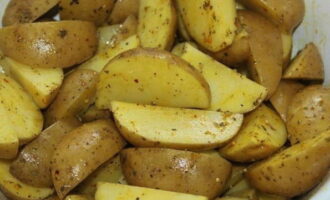 Погружаем в ароматную смесь картофельные дольки. Солим по вкусу и перемешиваем.