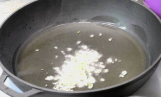 Затем приготовьте соус для тушения курицы. Очищенные зубки чеснока порубите ножом и немного обжарьте на другой сковородке в разогретом масле.