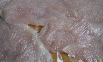 Через пищевую пленку, чтобы не повредить мясные волокна, филе немного отбейте молоточком с обеих сторон.