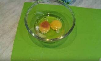 Для кляра в отдельную посуду разбейте два куриных яйца. К ним насыпьте соль с красным перцем и хорошо перемешайте.