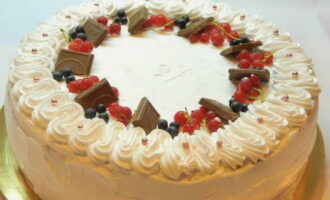 Украшаем торт сливками, ягодами и кусочками шоколада.