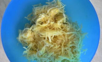 Подготовленную картошку натираем на крупной терке. Выкладываем массу в глубокую миску. Если овощ дал много сока, то слегка отжимаем от жидкости.