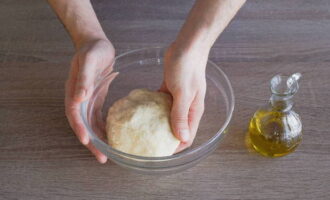 Руками замесите мягкое эластичное тесто. На это уйдет около 10 минут. Смажьте его оставшимся оливковым маслом.