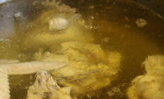 Заливаем куриные части и луковицу водой, ставим на плиту. Доводим содержимое до кипения, солим и варим до готовности курицы на умеренном огне. Периодически убираем пенку.