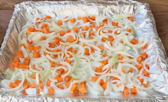 Морковку режем кубиками, лук нарезаем тонкими полукольцами. Выкладываем продукты на противень с фольгой, смазанной растительным маслом.