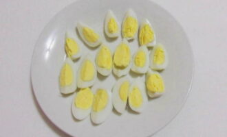 Отваренные и остуженные перепелиные яйца очистите от скорлупы и разрежьте на четвертинки.