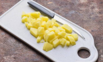 Картофель почистите, промойте и нарежьте небольшими кубиками, переложите в кастрюлю к сваренному гороху и варите еще 20 минут.