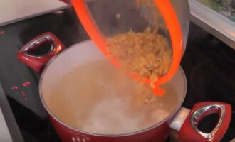Бульон повторно вскипятите, пересыпьте в него промытый горох, добавьте соль и поварите суп под прикрытой крышкой на небольшом огне в течение 40 минут.