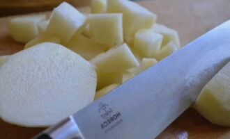 Картофель почистите от кожуры, промойте и разрежьте на большие куски. Переложите его в бульон и поварите еще 20 минут до полной готовности.