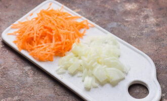 Пока суп варится, очищенную луковицу нарежьте маленькими кубиками, а морковь измельчите на крупной терке. 