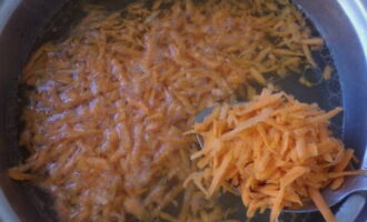 В бульон к сваренному до полуготовности картофелю переложите измельченную морковь и поварите 5 минут.