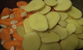 Очищенный картофель нарежьте кружками и уложите следующим слоем. Картофель посыпьте солью.