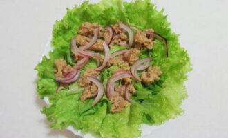 На порционные салатницы уложите листья салата. Поверх их положите кусочки тунца с маринованным луком.