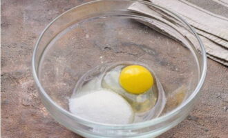 В тарелку с высокими бортами разбиваем яйцо, насыпаем два вида сахарного песка и немного соли.