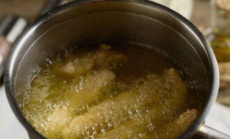 Опускаем курицу в кипящее масло и жарим около 3-4 минут на среднем пламени.