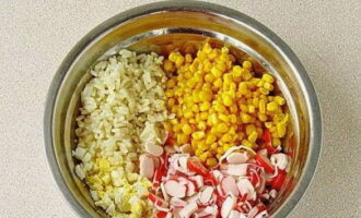 В салатник выкладываем крабовые палочки, рис, яйца и зерна сладкой кукурузы.