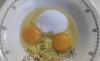 Разбиваем яйца в глубокую миску и дополняем из половиной сахара. Взбиваем до однородности.