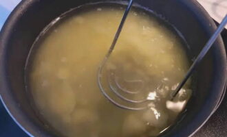 Сваренный картофель разомните толкушкой и переложите в бульон.