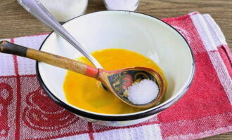В отдельную посуду разбить два куриных яйца и добавить соль с сахаром, количество которого можно увеличить, если готовите лапшевник детям.