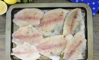 Каждый кусочек рыбного филе натираем солью и черным молотым перцем. Раскладываем продукт по противню, смазанному растительным маслом.