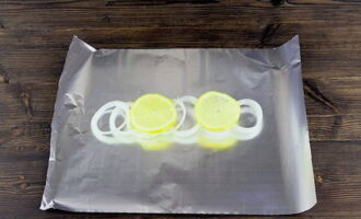 Отрезаем два прямоугольника фольги для запекания. На каждый кусочек фольги выкладываем немного лимона и лука.