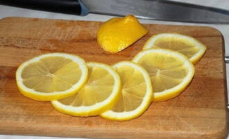 Промываем лимон и нарезаем его тонкими кружками. Кладем их внутрь подготовленных рыб.