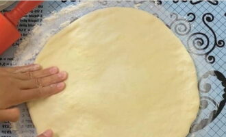 Руками разравниваем тесто и начинку, увеличивая диаметр. Затем проходимся скалкой до тех пор, пока толщина полуфабриката не будет составлять 2-3 сантиметра. 