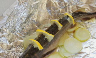 На хребте у рыб делаем надрезы и вставляем полукольца лимона, кладем осетров отдельно друг от друга на овощную «подушку».
