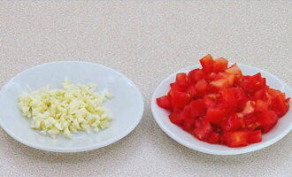 На кубики режем чеснок и томаты.