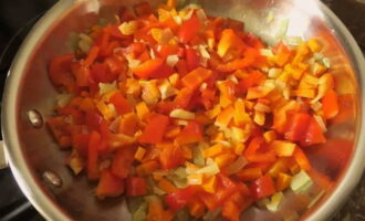 Когда морковка дойдет до стадии полуготовности, отправьте к овощам болгарский перец, нарезанный кубиком.
