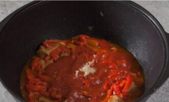 Далее дополняем кушанье томатной пастой, измельченным чесноком, а также солью и молотым перцем.