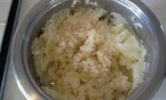 Отварной картофель слейте, сдобрите прогретым молоком и превратите массу в картофельное пюре. Далее отправьте пассерованный лук и объедините ингредиенты. Для соуса смешайте измельченный чеснок и зелень, посолите, посахарите, приправьте перцем и разбавьте сметаной.