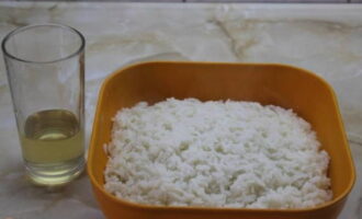 Сваренный рис переложите в плоскую посуду, полейте рисовым уксусом, перемешайте и оставьте для остывания.