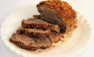 Запеченное мясо переложить на блюдо и нарезать поперек мясных волокон порционными  кусочками.
