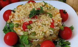 Приготовленный на сковороде рассыпчатый рис с овощами разложите по порционным тарелкам.