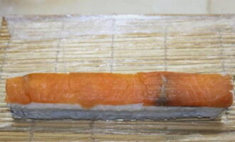 Поверх сформированного ролла плотно уложите пластинки лосося.