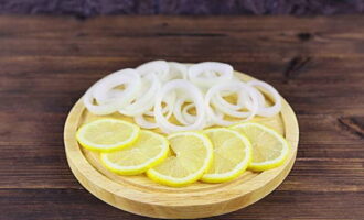 Лимон ошпарьте кипятком, обсушите, порежьте кружочками. Обшелушенный лук  нарежьте не слишком тонкими кольцами.
