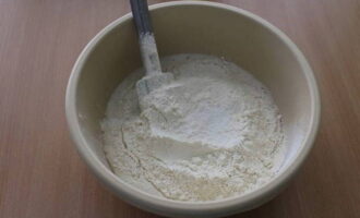 В опару всыпьте просеянную муку, соль и влейте оставшуюся воду. Начинайте замешивать тесто ложкой или лопаткой.