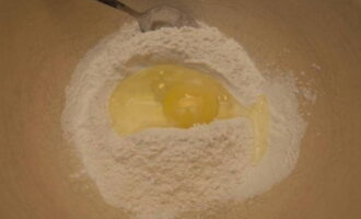 Сначала приготовим тесто. Просеиваем в глубокую миску муку. Разбиваем к ней куриное яйцо и вливаем воду, предварительно размешанную с солью.