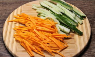 Тонкими продолговатыми ломтиками нарезаем очищенную морковку и промытый огурец.