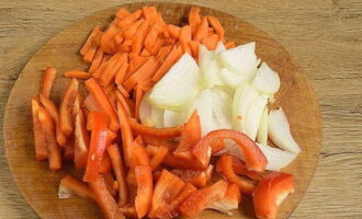 Болгарский перец очищаем от семян и режем тонкой соломкой. Также режем соломкой очищенную морковь, тонкими полукольцами разделываем репчатый лук.