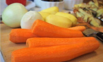 Параллельно вооружаемся овощечисткой и снимаем кожуру  с картошки и моркови. Лук очищаем от шелухи.