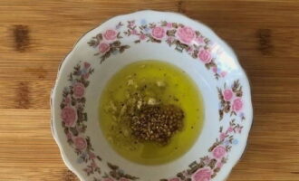 В глубокой тарелке соединяем оливковое масло, лимонный сок, дижонскую горчицу, измельченный зубчик чеснока, щепотку соли и черный молотый перец. Хорошо вымешиваем.