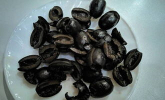 На половинки разрежьте черные оливки.