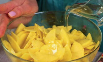 Поливаем картошку растительным маслом и перемешиваем для равномерного распределения соли и специй.