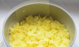 Начинаем формировать закуску. Отварной картофель остужаем, натираем на крупной терке. Укладываем продукт ровным слоем внутрь формы.
