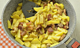 Перемешайте содержимое сковороды, закройте ее крышкой и готовьте блюдо на среднем огне в течение 5-7 минут. По истечении указанного времени посолите, и приправьте картошку и свинину по вкусу.
